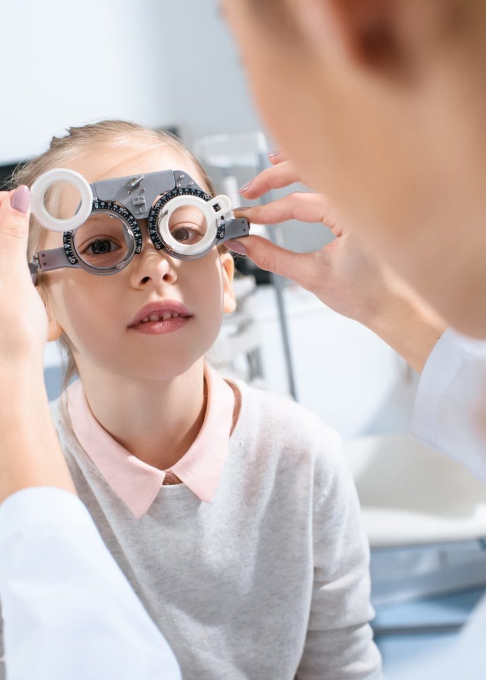 selective focus of ophthalmologist examining kid eyes with trial frame in clinic