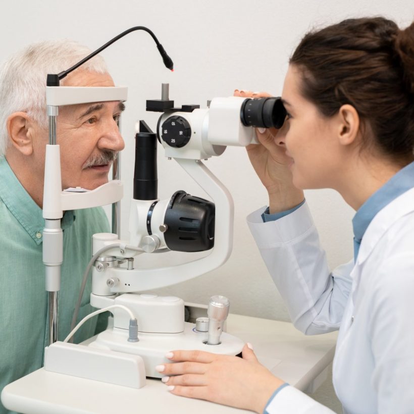 Young brunette female ophthalmologist testing eyesight of senior male patient