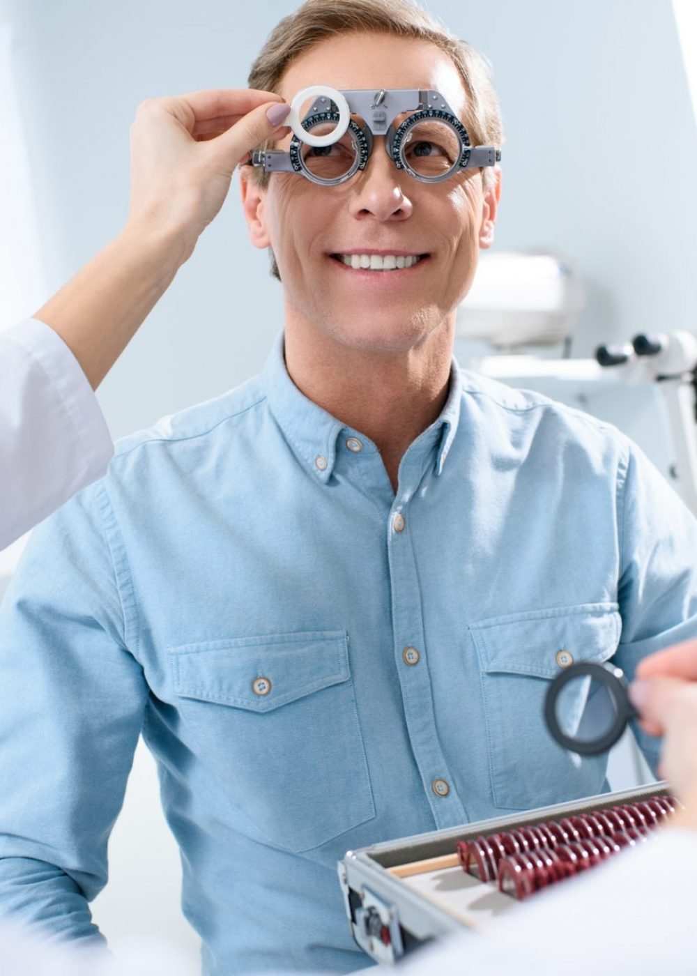 ophthalmologist examining middle aged man eyes with trial frame and lenses
